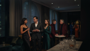 People mingling at a cocktail party, some wearing little black dresses.