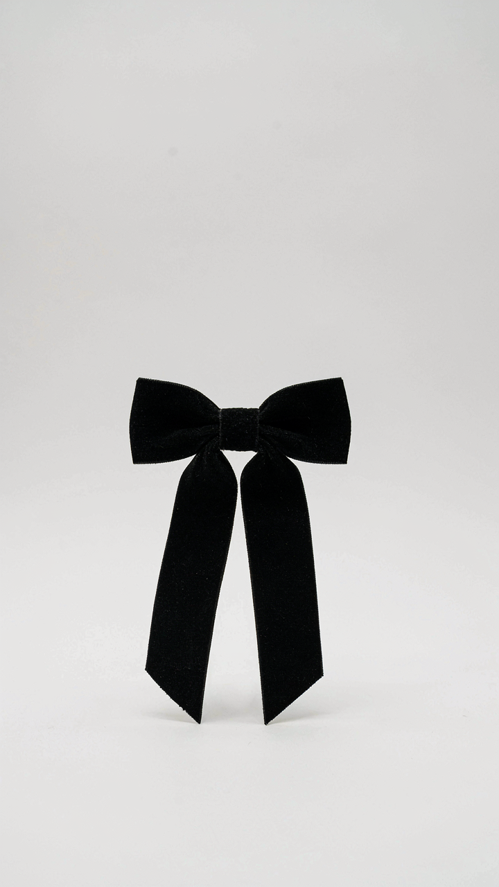 White canvas with a single, black velvet bow centered on it.