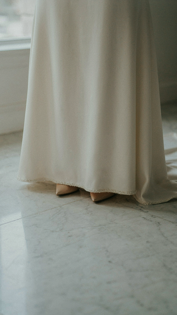 A floor-length gown's hemline touches the ground, showing elegant shoes.