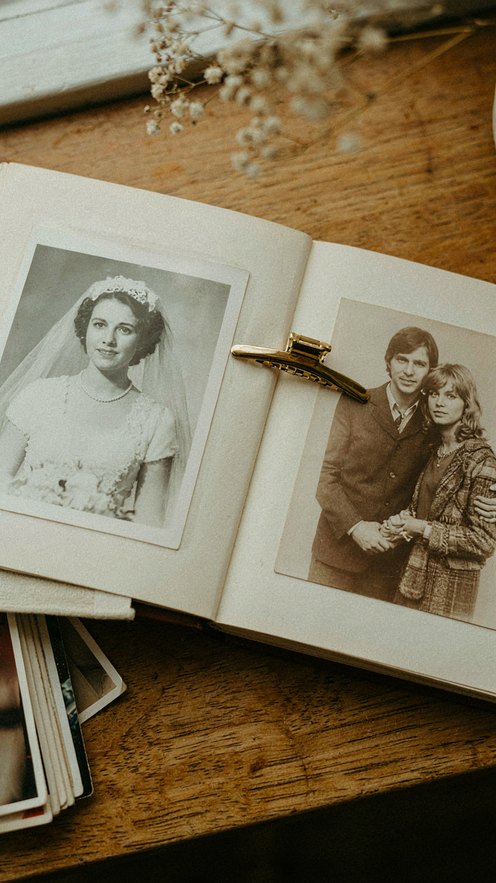 A classic gold metal hair clip rests on an old photo album.