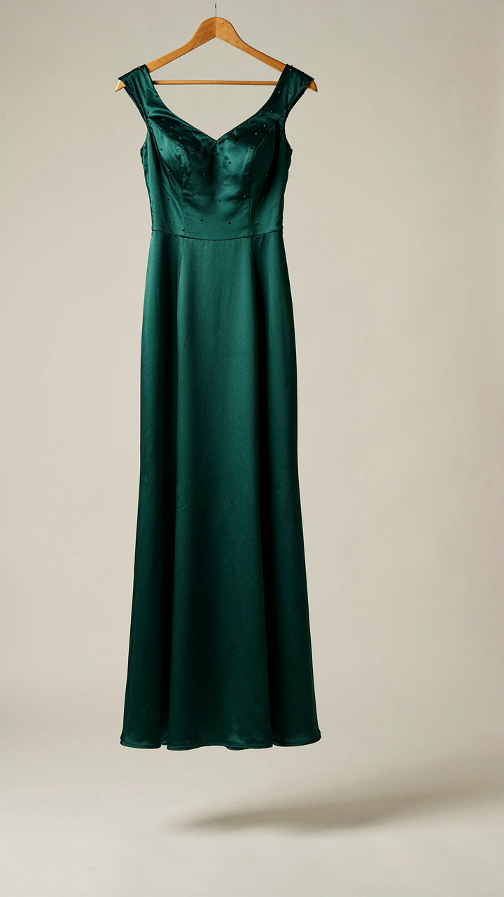 A midi-length maid of honor gown in a rich jewel tone hangs straight on a hanger.