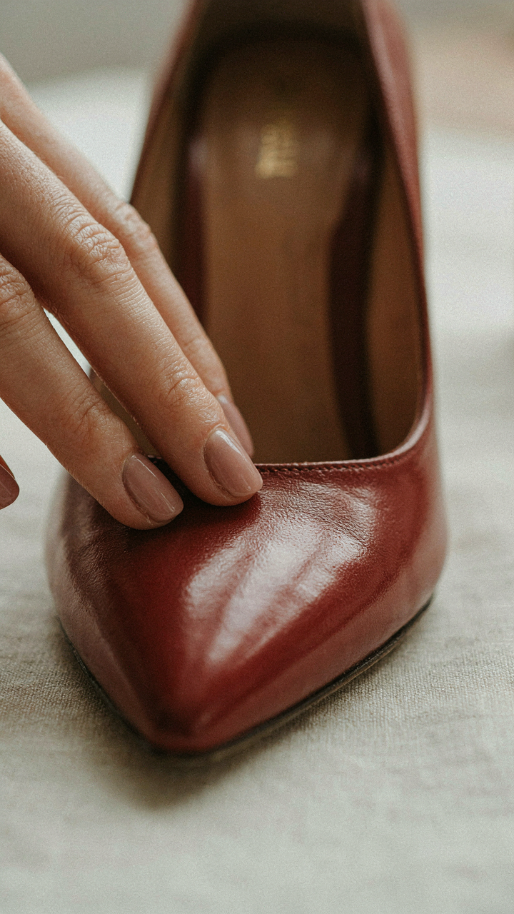 A hand presses on the soft leather of a new high heel shoe.