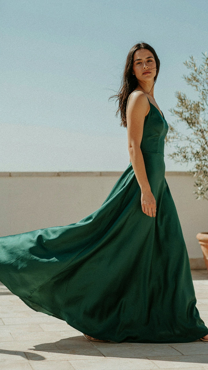 A woman in a satin maxi dress, showing exaggerated fabric flow.
