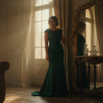 A woman in an elegant dress striking a confident pose for a mirror selfie.
