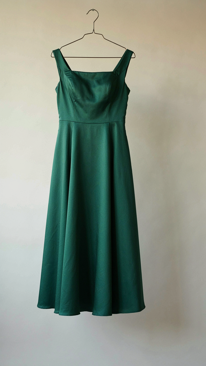 A sophisticated knee-length A-line dress in a jewel tone hangs on a hanger.