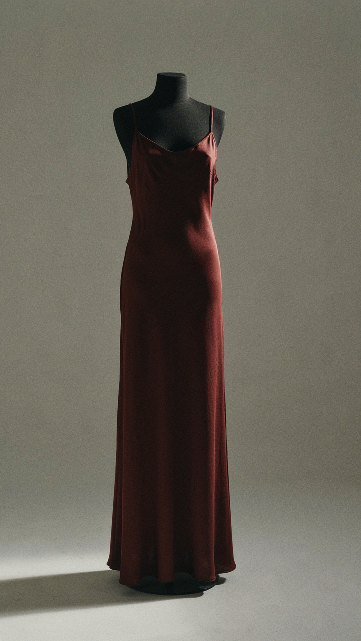 A deep burgundy silk dress glows in warm indoor light.