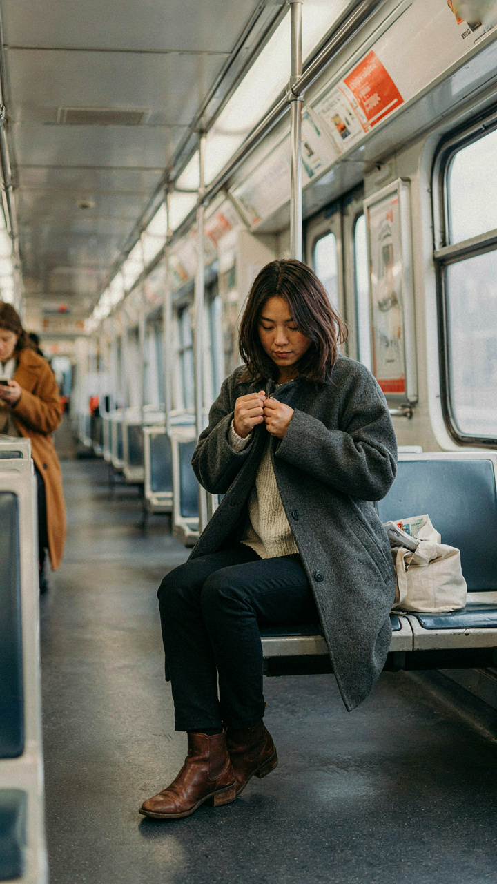 A person adjusts their jacket inside a warm subway car in winter.