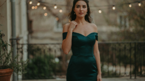 Woman in an elegant off shoulder cocktail dress on a patio at dusk.