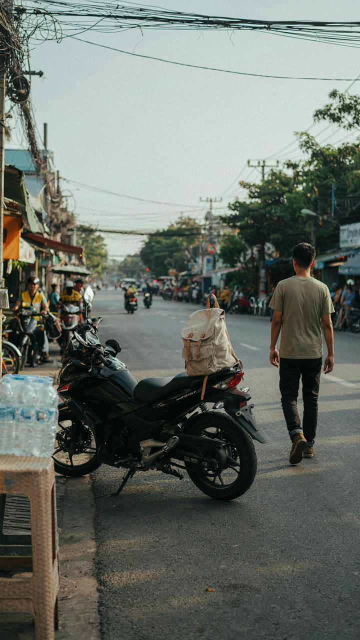 A small backpack leans against a motorcycle on a busy street.