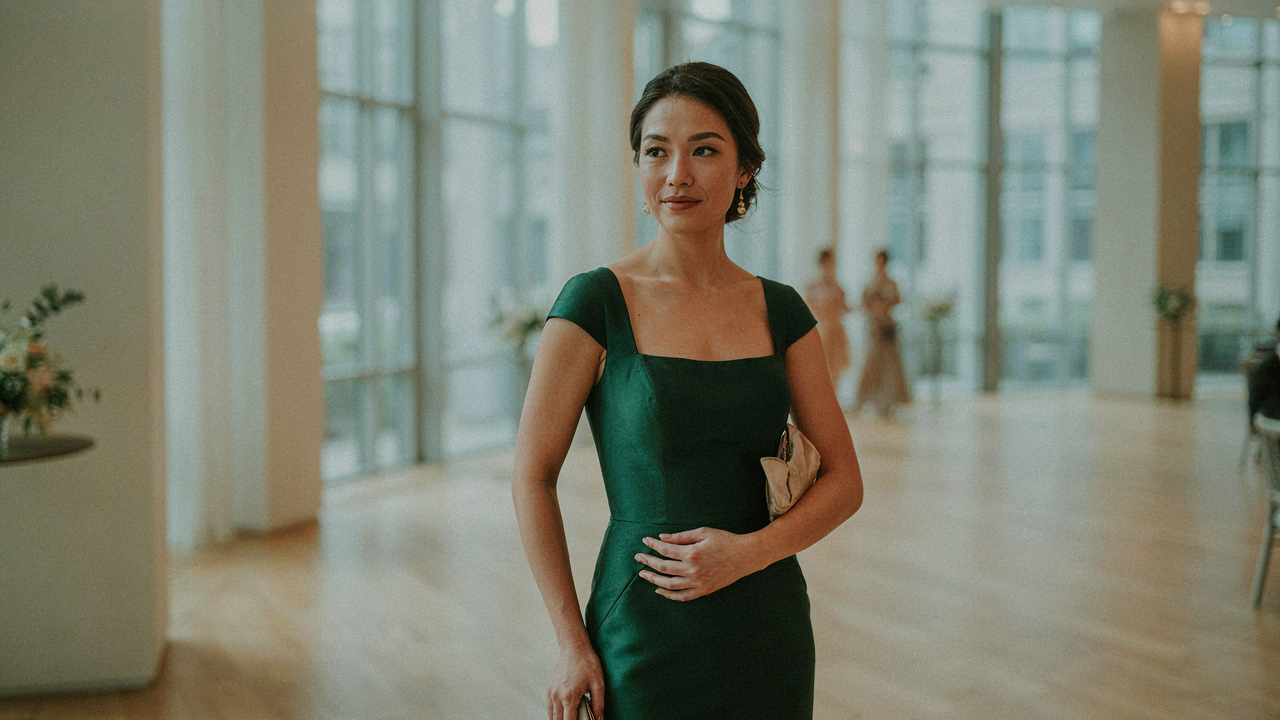 A woman in a stylish emerald green dress with a structured neckline, looking confident.