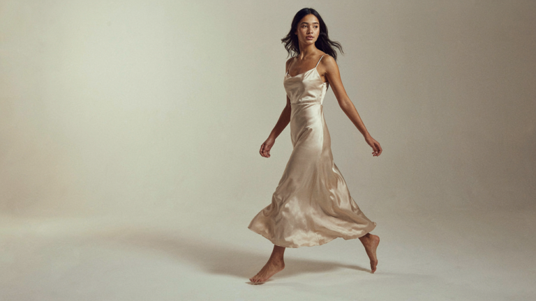 A woman in a satin dress captured mid-movement, fabric flowing dynamically.