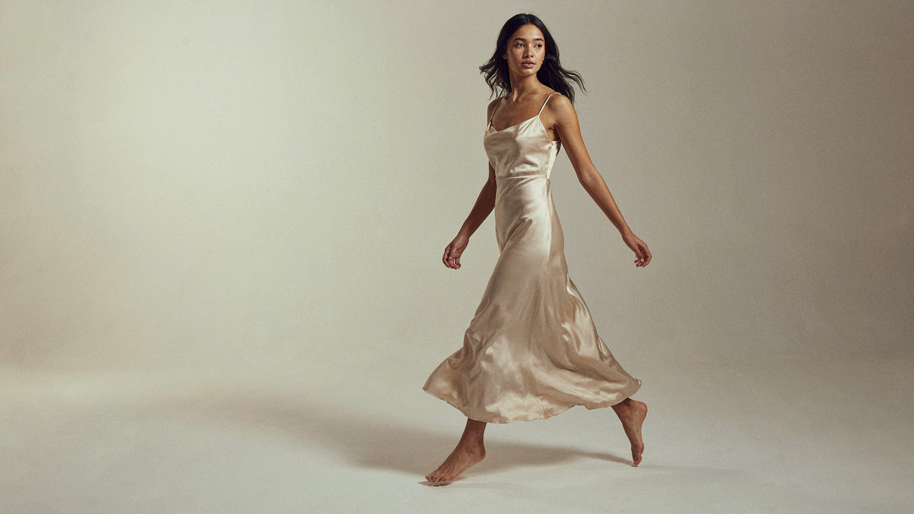 A woman in a satin dress captured mid-movement, fabric flowing dynamically.