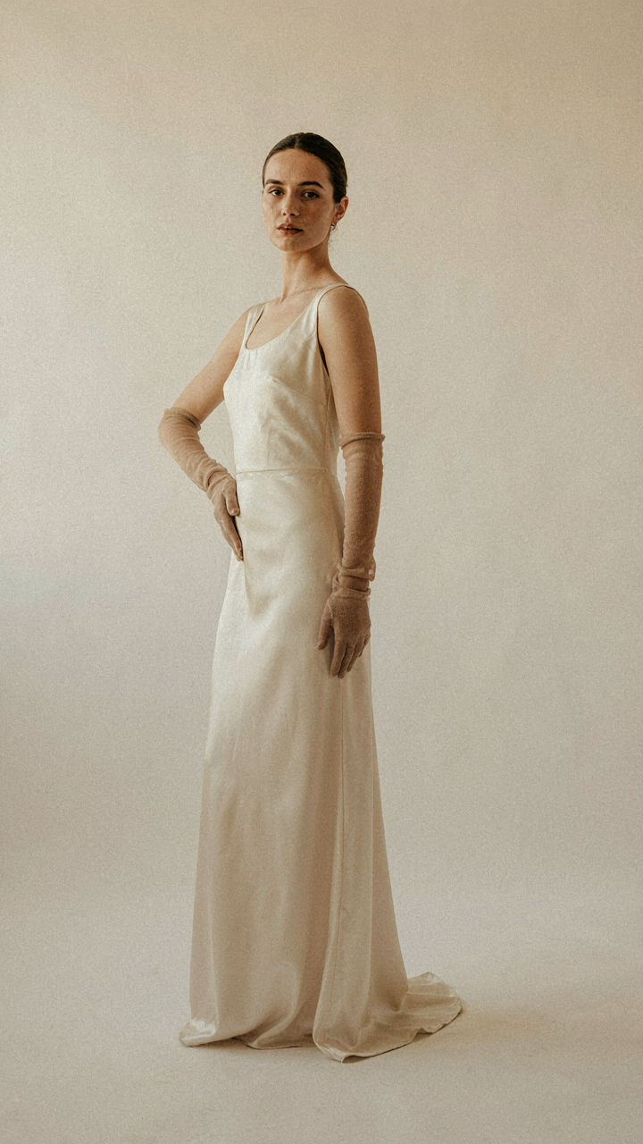 A hand in a matte jersey elbow-length glove with an evening dress.