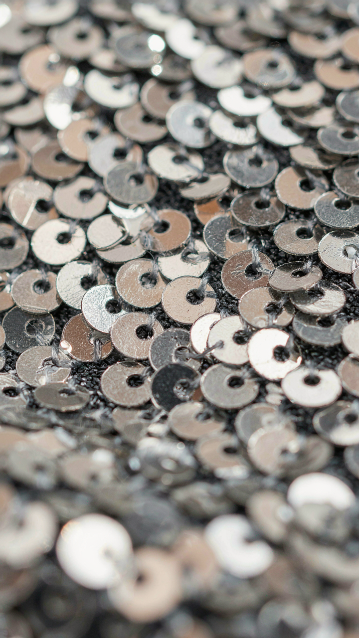 Individual sequins on fabric, some glinting, others muted.