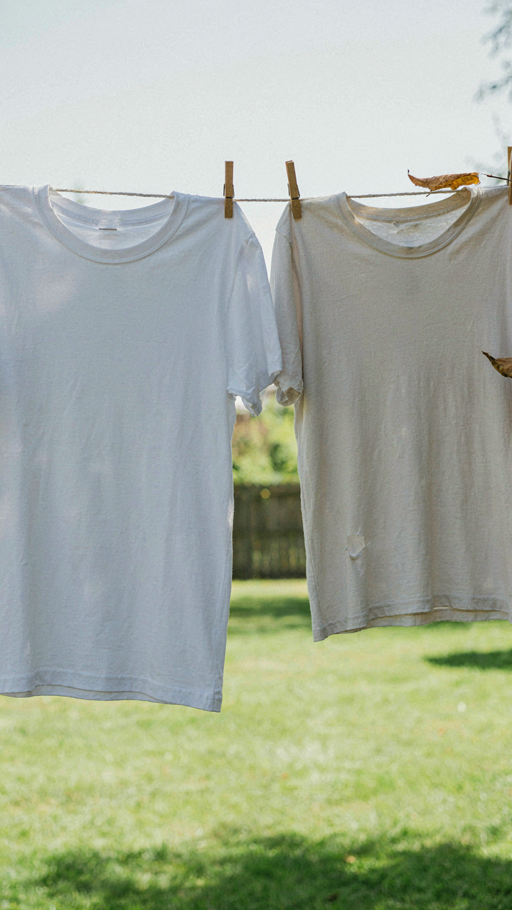 A new white t-shirt next to a worn, faded, and pilled t-shirt on a line.