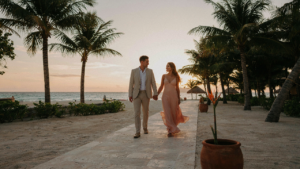 A stylish couple in resort formal attire walks a resort path at sunset.