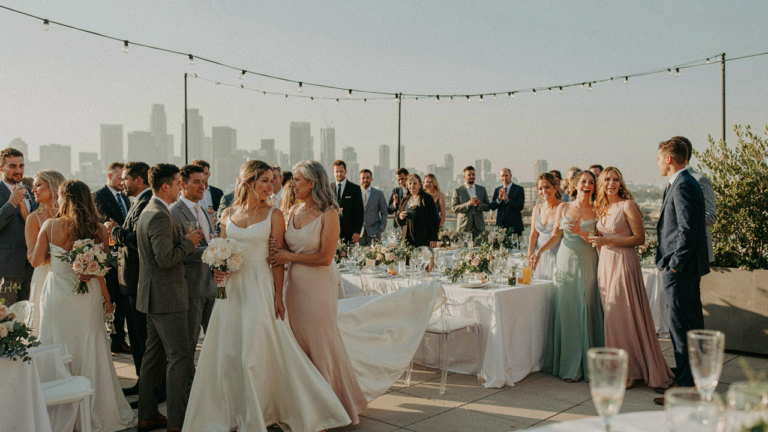 Guests in elegant rooftop wedding attire mingle on a chic city rooftop.