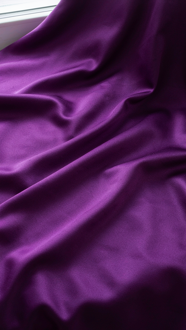 Close-up of luxurious deep purple satin fabric with a natural sheen.