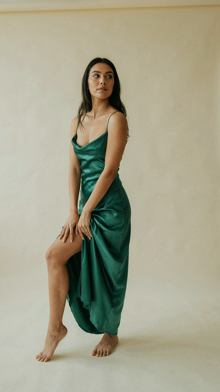 A woman in a satin dress, fabric pooling due to a shifted hip.