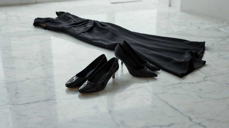 Elegant black patent leather flats and high heels next to a formal black gown.