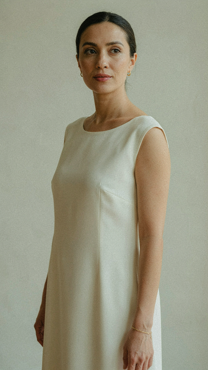 A woman in a perfectly tailored, simple cream-colored gown.