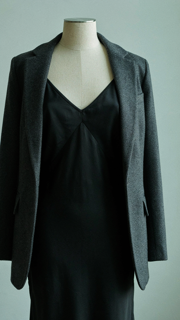 A black satin slip dress is worn under an open charcoal wool blazer.