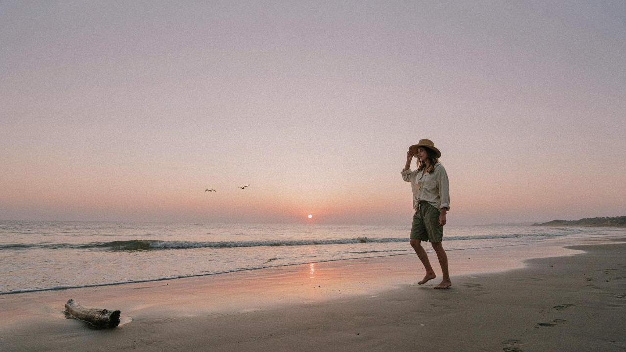 One person in solo beach trip outfits walks on a secluded beach at sunrise.
