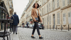 A woman in a blazer walks on a city street, embodying solo female travel outfits.