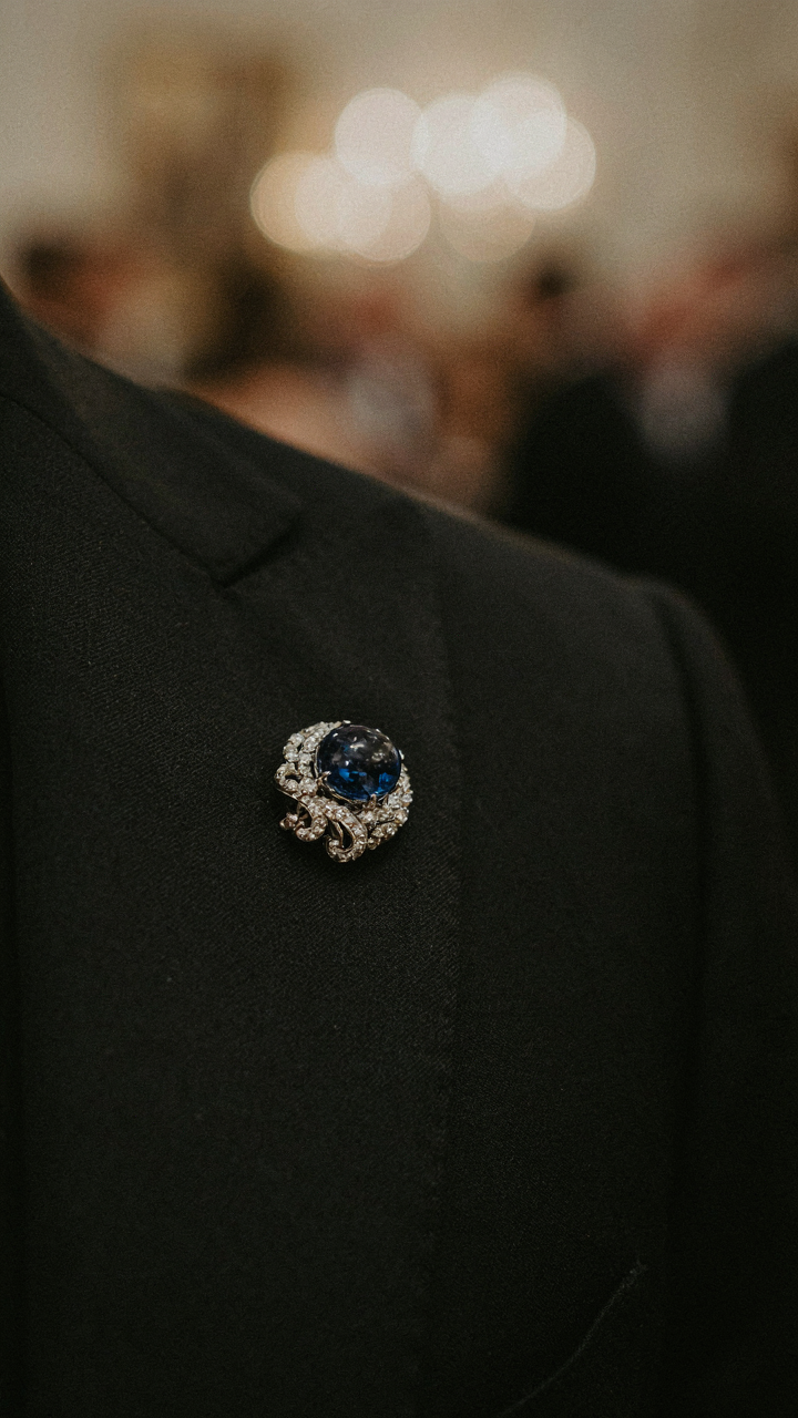 An exquisite sapphire brooch is pinned to a black silk lapel.