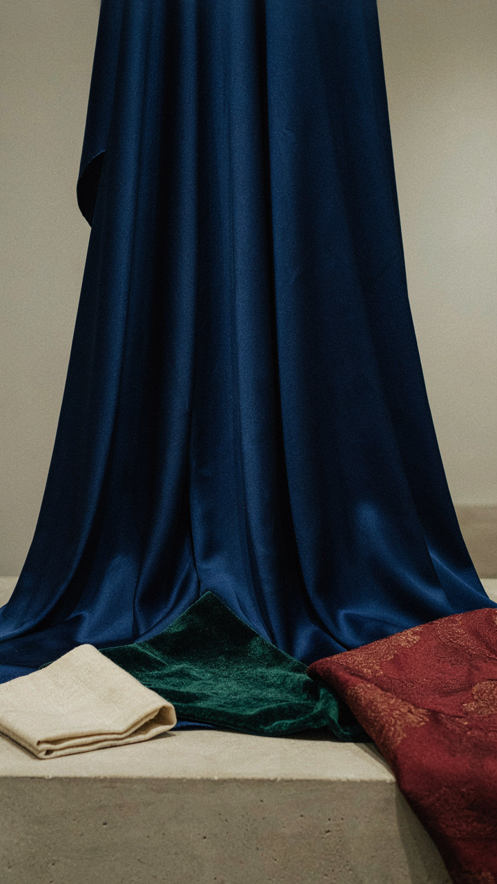 Display of rich jewel tone fabrics in sapphire, emerald, and burgundy.