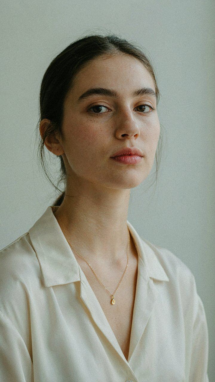 A woman's face is gracefully framed by a delicate necklace.