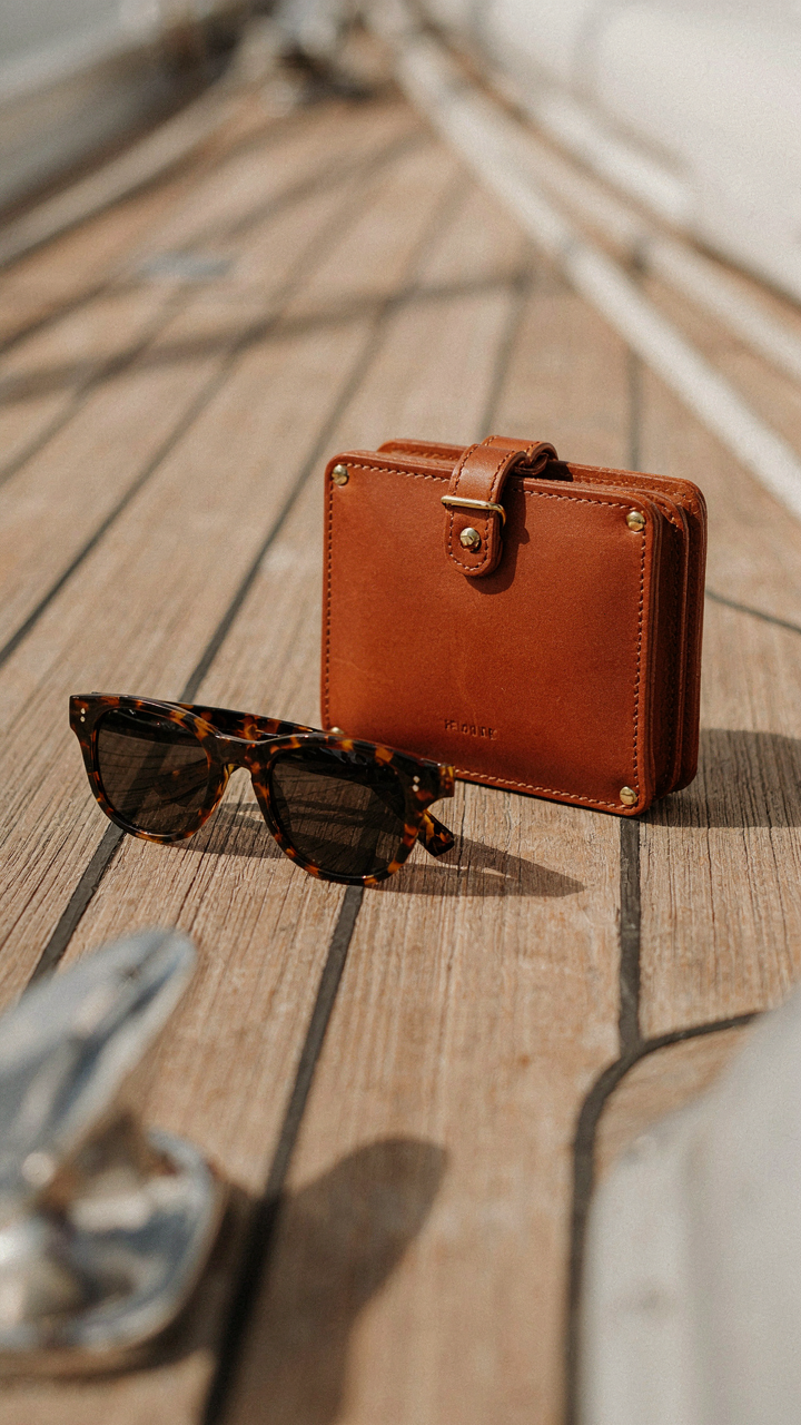 Polarized sunglasses and a structured bag sit on a yacht table.
