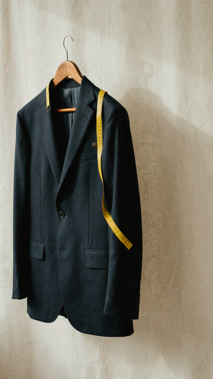 A measuring tape on the fitted sleeve of a navy blazer.