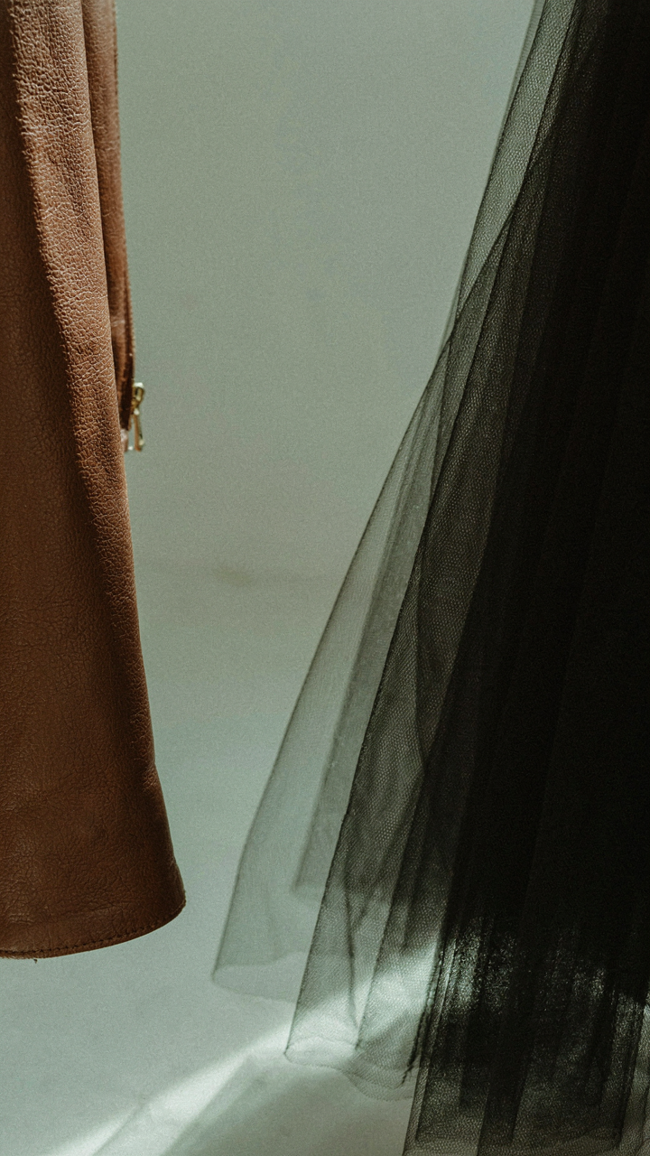 A close-up of a leather jacket sleeve next to a sheer black tulle skirt.