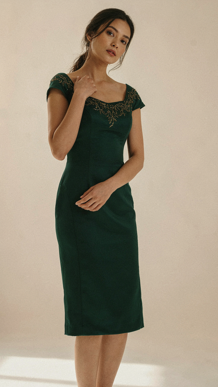 Woman in a square neck dress with metallic embroidery on the collarbone.