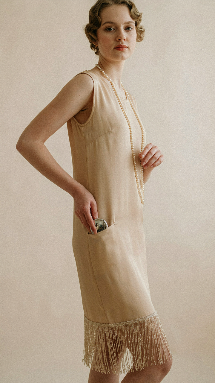 Vintage 1920s dress with a hand placing a compact mirror into a hidden pocket.