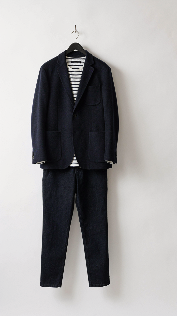 A navy blazer, striped shirt, and dark jeans hang on a hanger.
