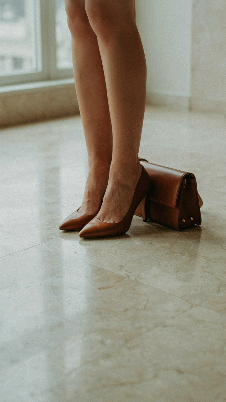 Elegant leather shoes and a matching handbag on a polished floor.
