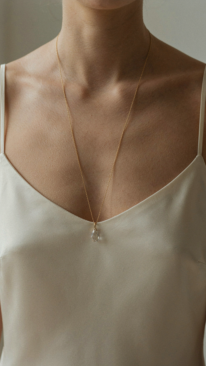 A long pendant necklace hanging to mid-sternum, creating a strong vertical line.