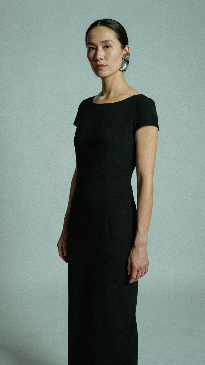 Woman in a simple black gown with one sculptural earring.