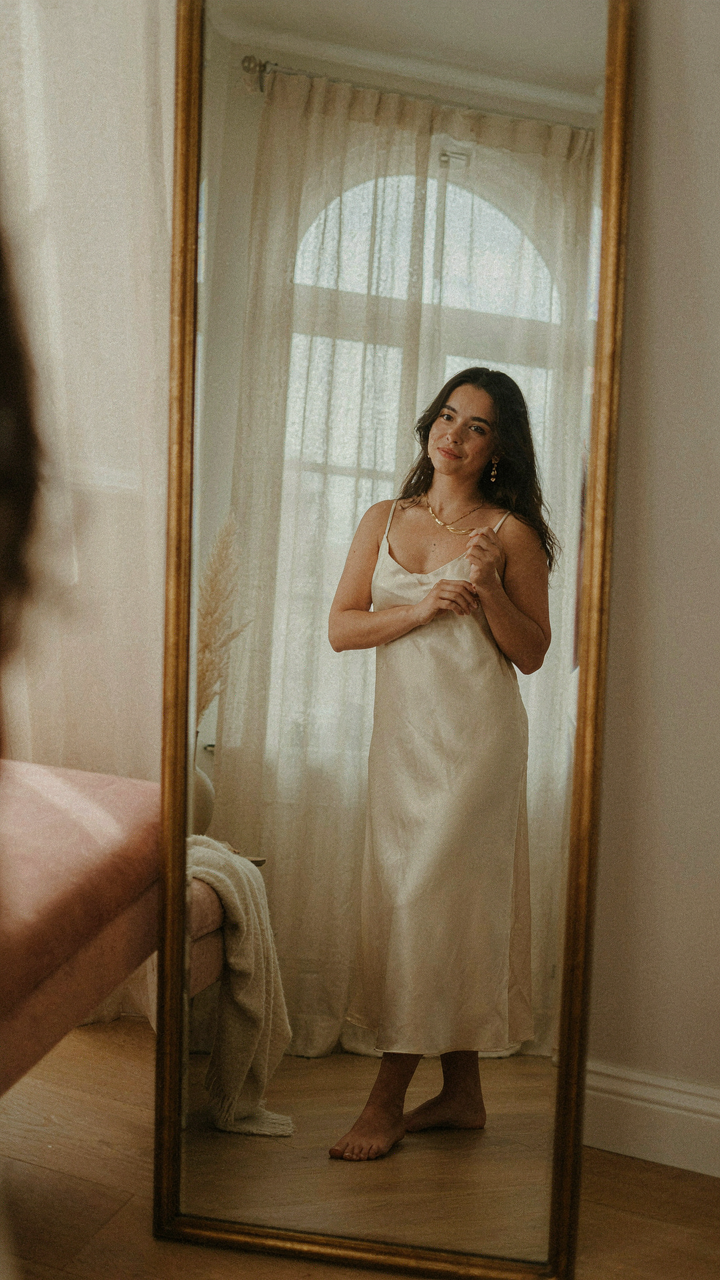 A person takes a selfie of their formal dress, necklace, and earrings.