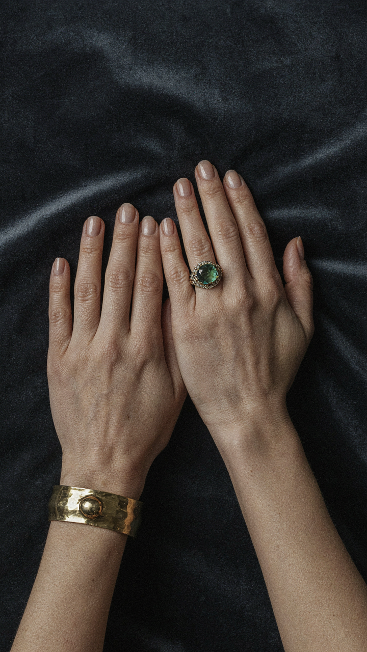 A woman's hand with an ornate cocktail ring and a substantial bracelet.