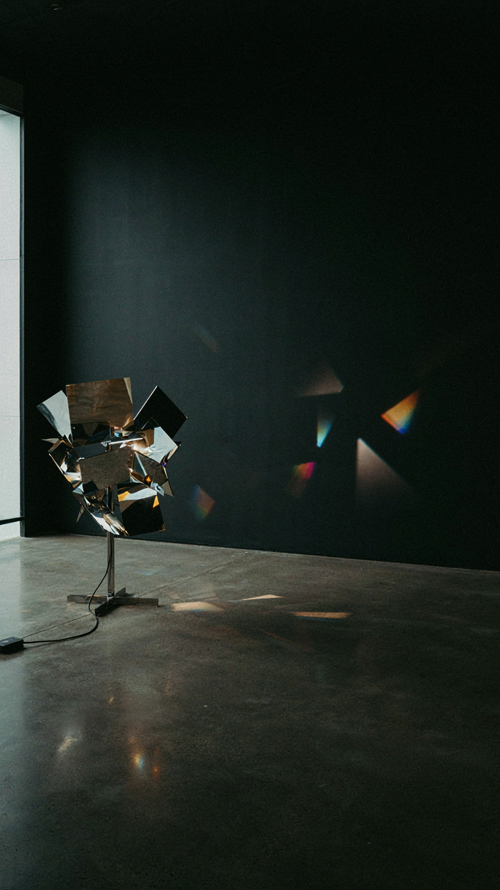 Fragmented metallic surfaces in a light art installation create dynamic light patterns.