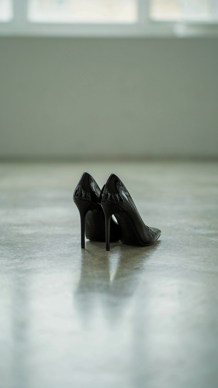 A pair of sharp black pointed-toe stiletto heels on a polished floor.