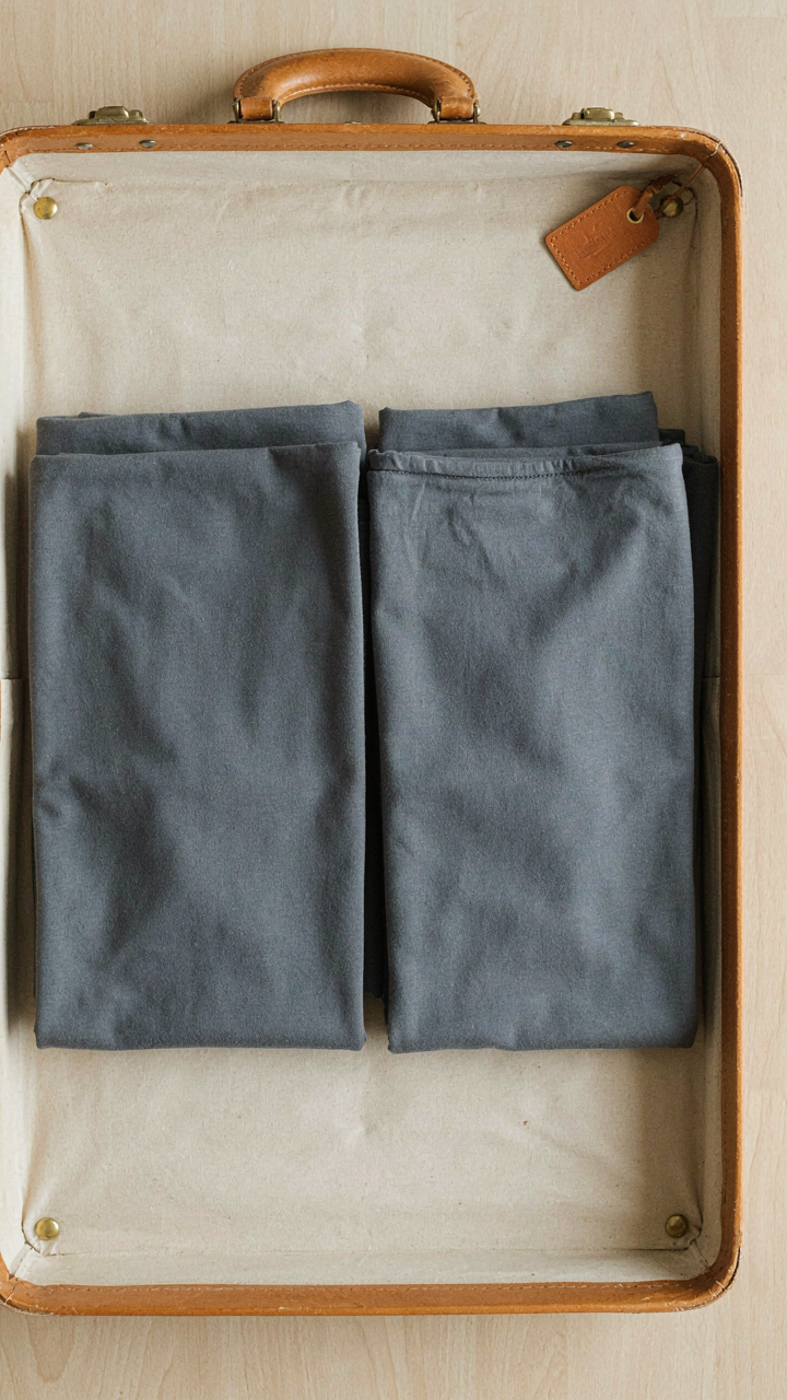Two identical t-shirts are neatly folded in a suitcase for solo travel.
