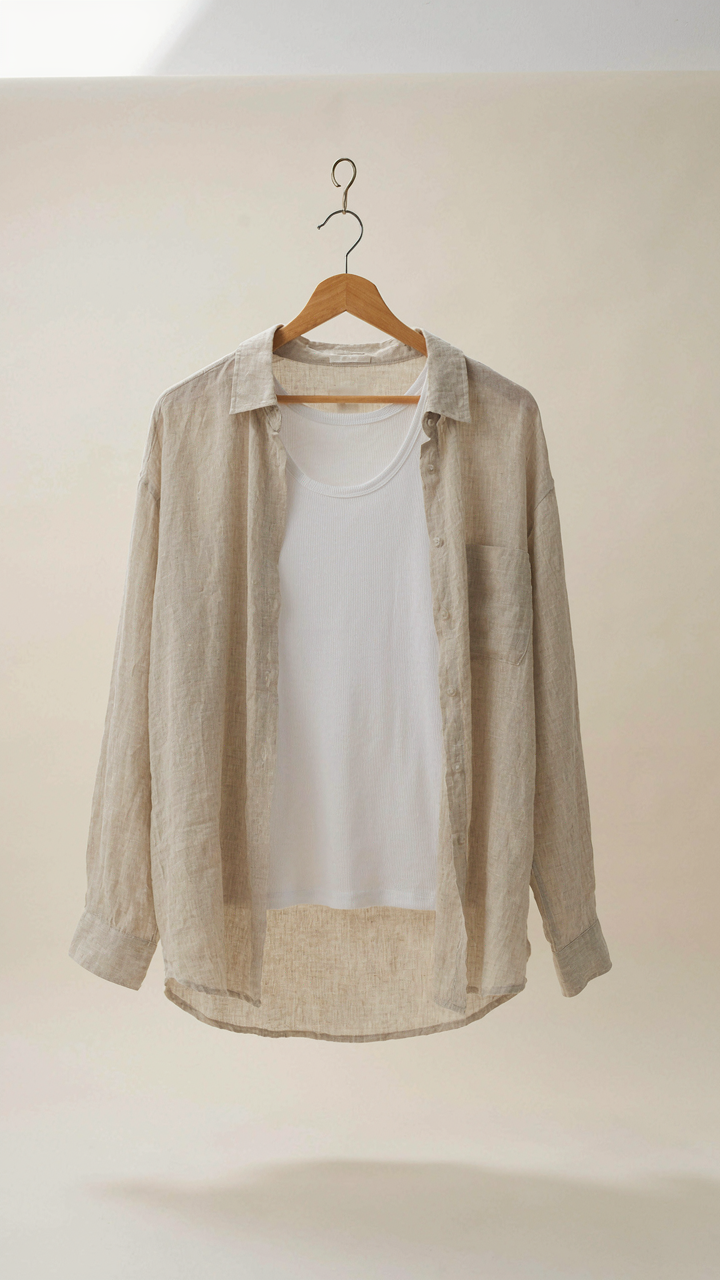 A lightweight linen shirt draped open over a white tank top on a hanger.
