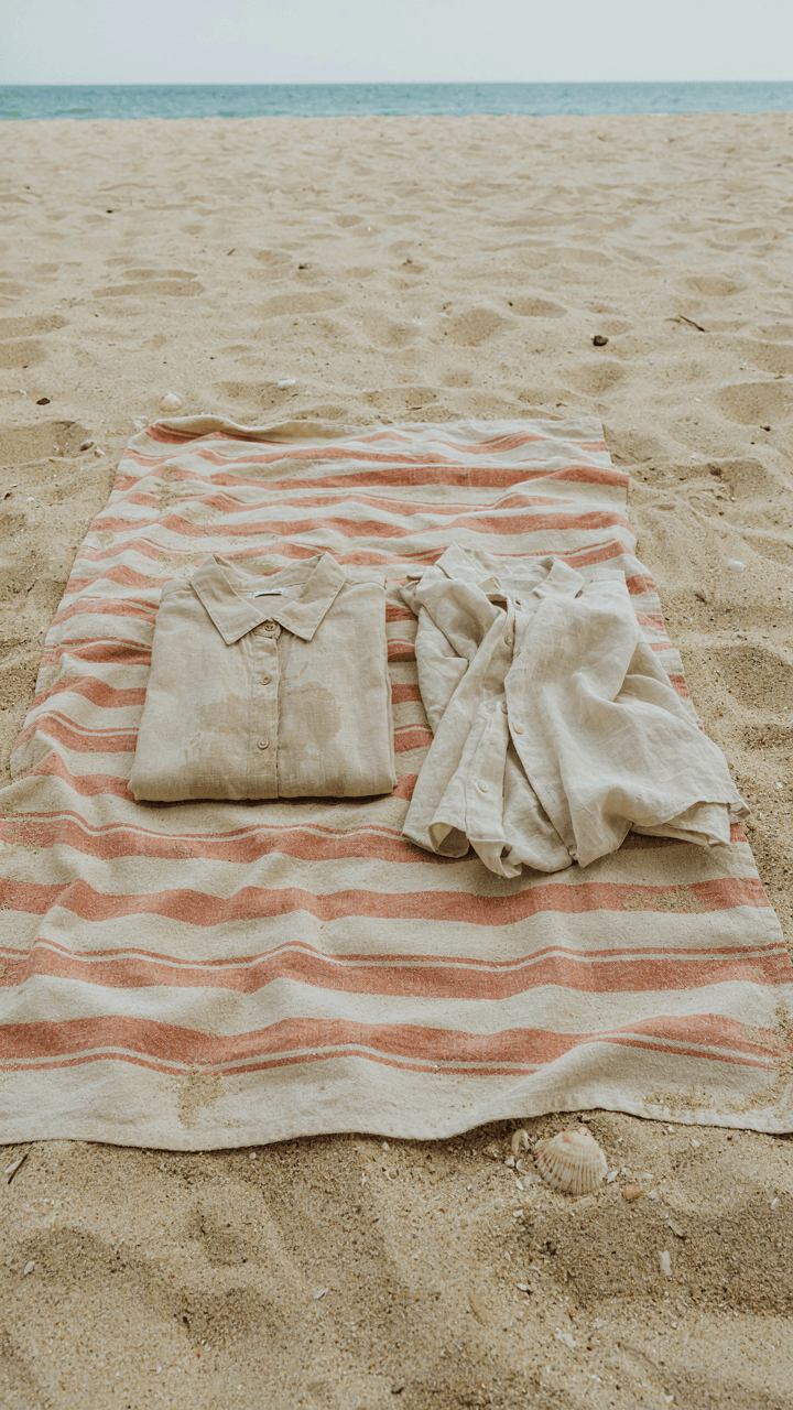 A neat linen-cotton blend shirt next to a wrinkled pure linen shirt on sand.