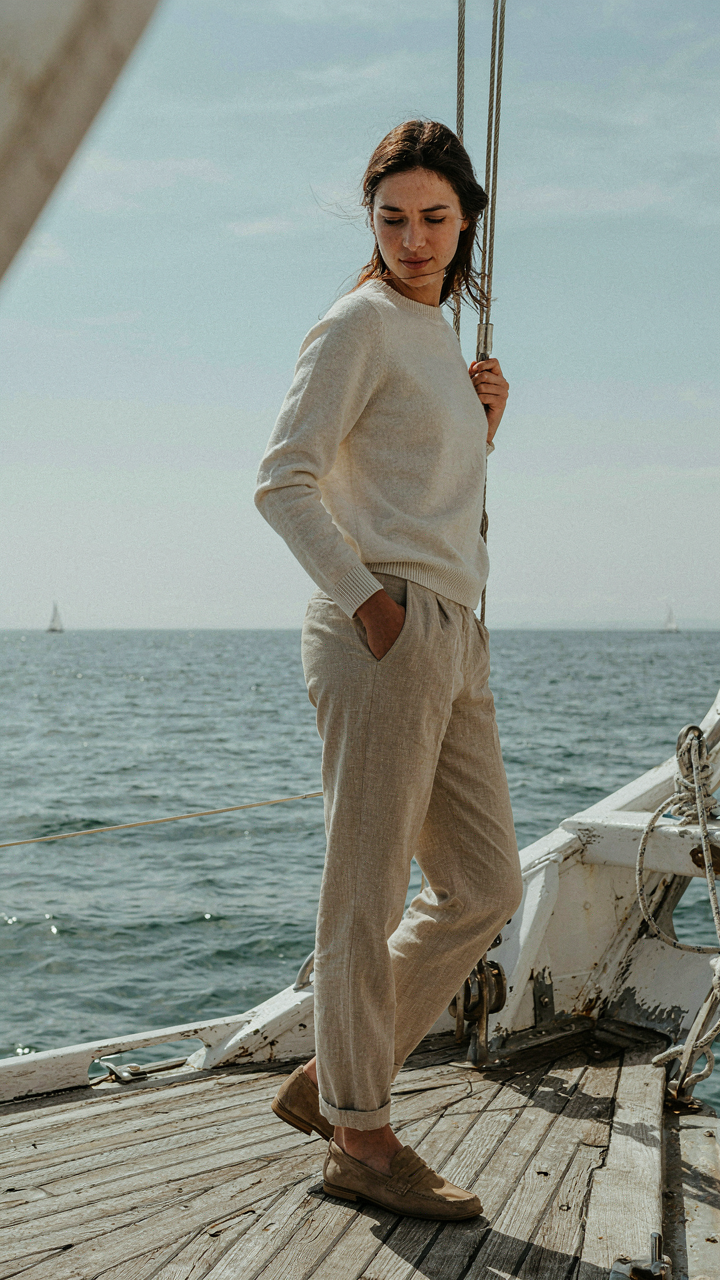A person on a ship deck looks comfortable in merino wool and linen clothes.