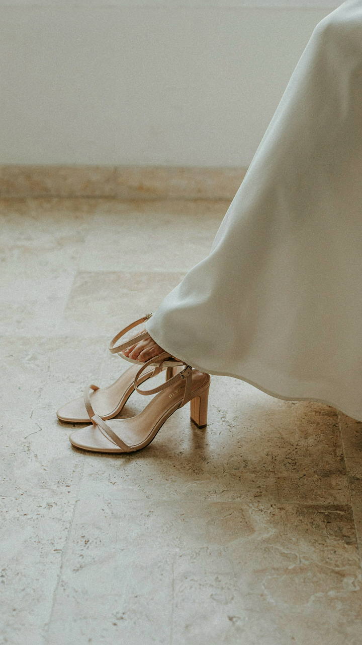 Elegant, low-heeled strappy sandals next to a flowing dress hem.