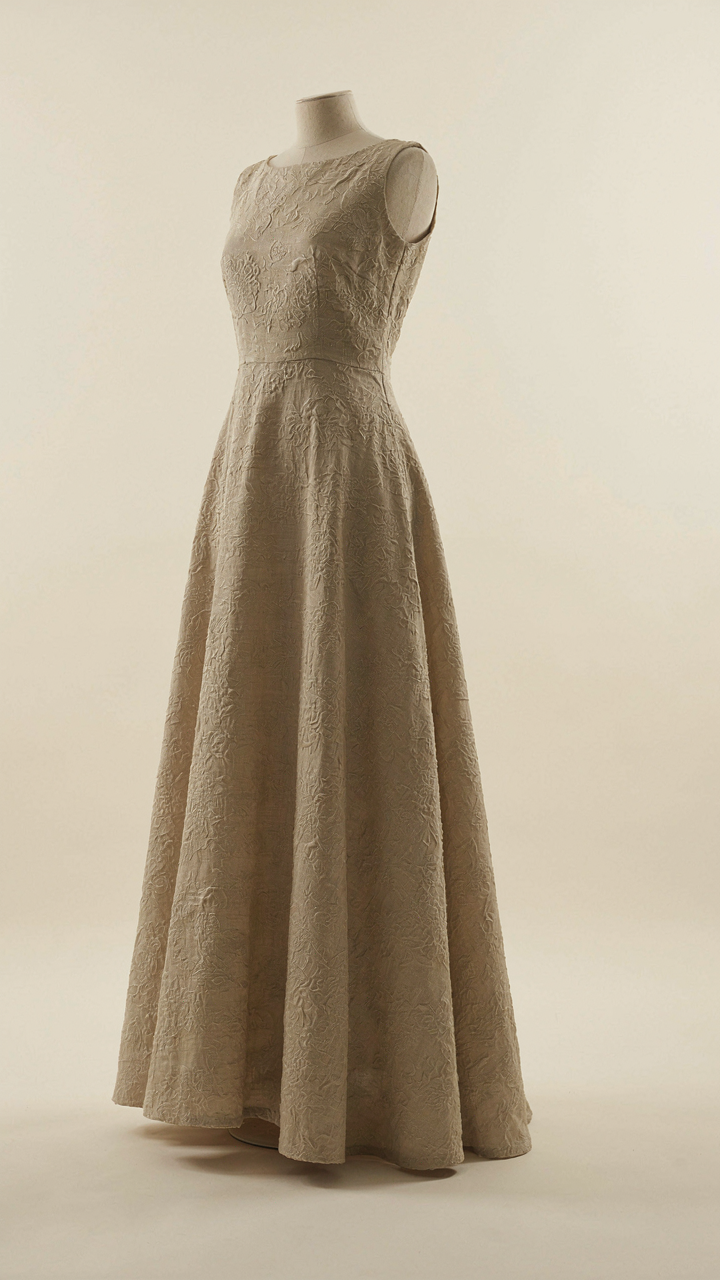 A beige dress with a subtle jacquard weave texture, showing its dimension.